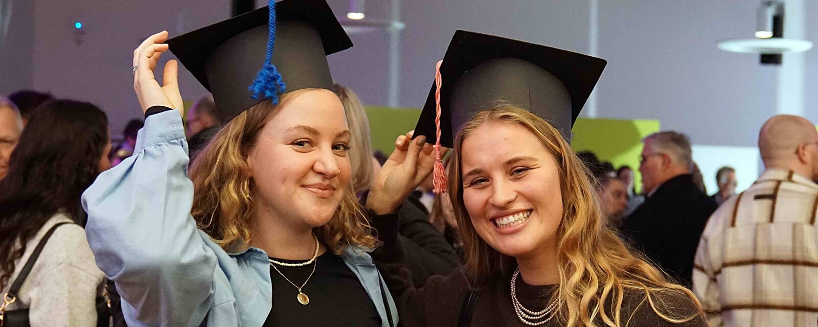 Zu sehen sind zwei Alumni der PHHD mit selbstgebasteltem Graduiertenhut.