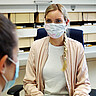 Das Bild zeigt eine Mitarbeiterin des Studienbüros der Hochschule, die eine andere Frau berät. Beide tragen aufgrund der Corona-Pandemie eine Maske. Copyright: Pädagogische Hochschule Heidelberg..