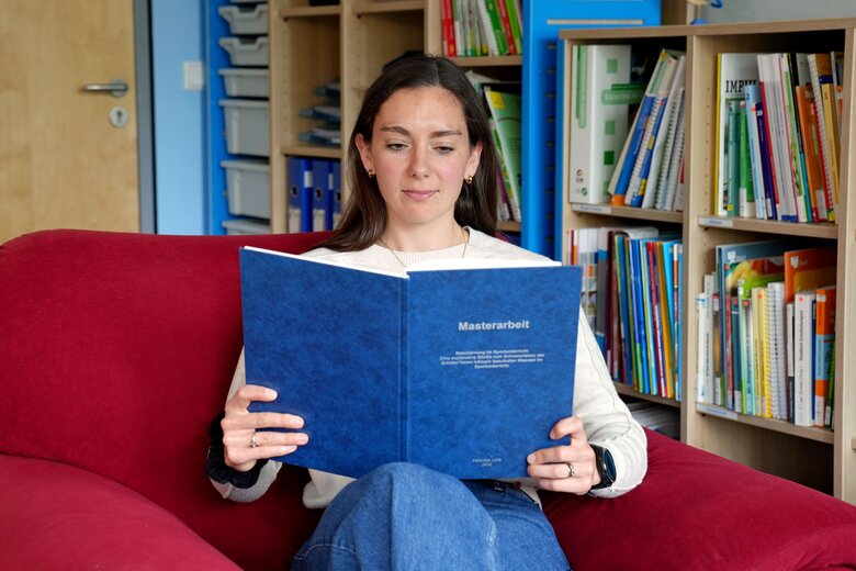 Zu sehen ist eine Studentin, die ein Sportbuch liest.