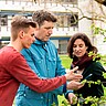 Drei Personen betrachten Äste an einem Baum