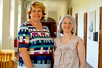 Das Bild zeigt links Karin Terfloth und rechts Vera Heyl. Sie stehen im Altbauflur der Hochschule und lächeln in die Kamera.