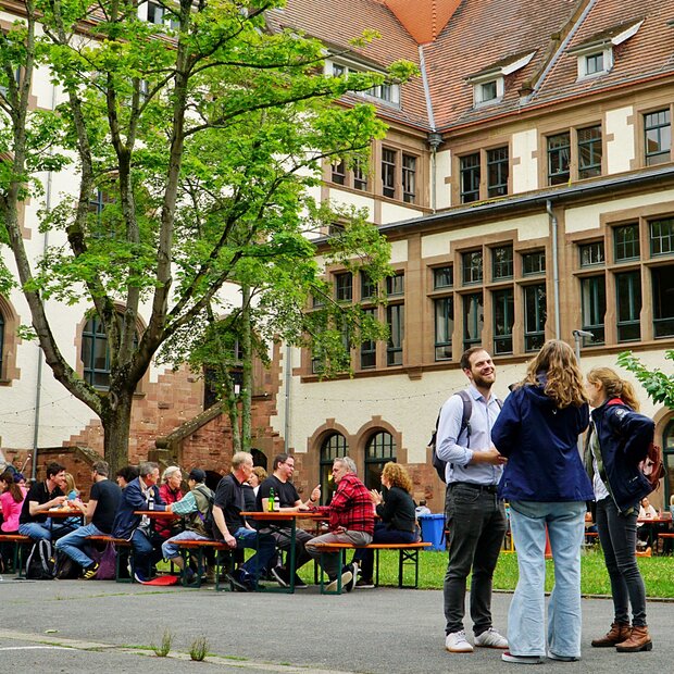 Symbolbild, bei dem Menschen m Innenhof der Alten PHHD im Gespräch sind.
