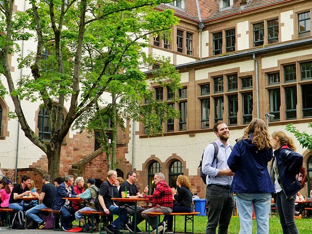 Symbolbild, bei dem Menschen m Innenhof der Alten PHHD im Gespräch sind.