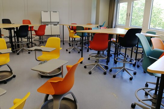 Abgebildet ist das Active Learning Center der PH. Bunte Stühle zum herumrollen, sowie Stehtische mit extra hohen Stühlen und beschreibbare Weißwandtafeln 