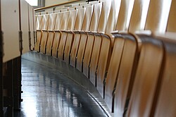 Das Bild zeigt hochgeklappte Stühle in einem Hörsaal der PH.
